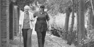 an old woman being supported by a nursing assistant for the elderly during a walk