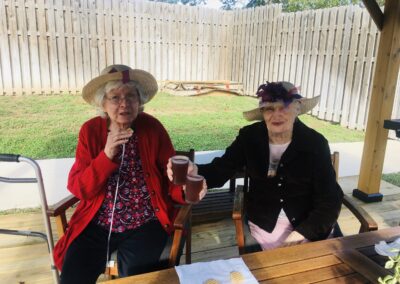 residents sitting at table outside with drinks toasting