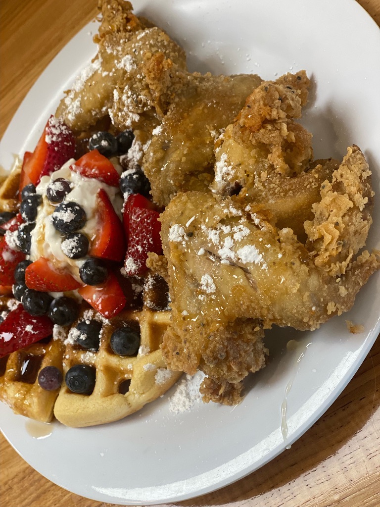 fried chicken and waffles topped with berries and whipped cream