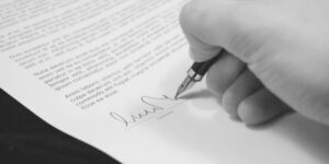a hand signing a legal document with a fountain pen